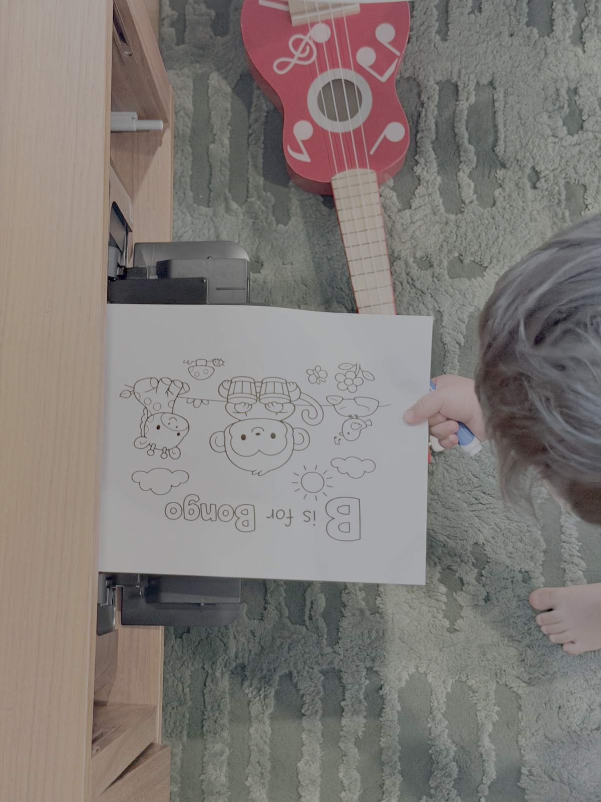 A child taking a freshly printed coloring page from a home printer